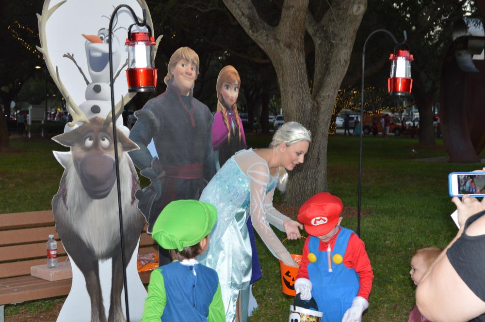 Young woman dressed as Elsa handing out candy